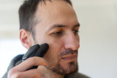 Yakışıklı, üstsüz, sakalını jiletle tıraş eden bir adamın yakın portresi..