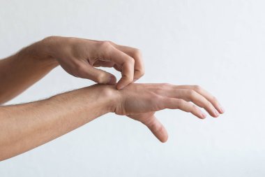 Deri iltihabı, egzama, alerji, sedef hastalığı. Kolunu kaşıyan bir adam, gri stüdyo arka planı. Adam kaşınıyor dirseğinde, kopyala boşluğu.