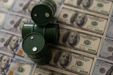 Dolar banknotlarının üzerinde duran üç varil petrol. Petrol işi, satış, üretim, takas, ticaret geliri