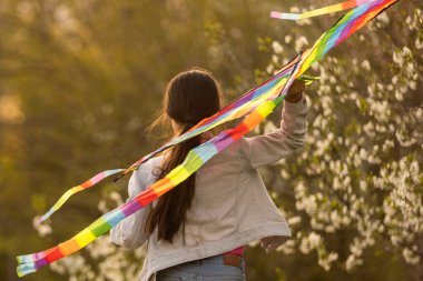 Küçük tatlı kız güneşli bir günde uçurtma uçuruyor..