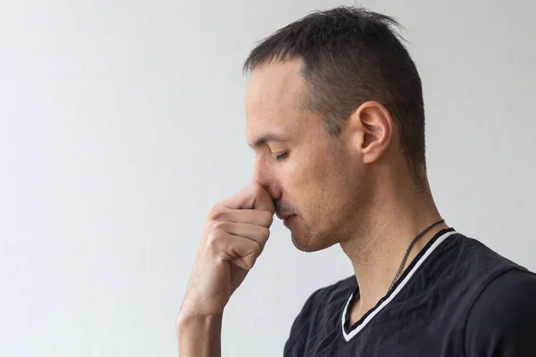 Man smells something stinky and pinches his nose to stop the bad odor.