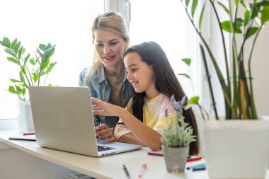 Küçük having oyunculuk online uygulama ile video çizgi film izlerken veya dizüstü bilgisayarda birlikte oyun oynayan çocuk kızı, Genç çocuk bakıcısı veya bilgisayar kullanmak için kız çocuk öğretim dadı ile mutlu anne.