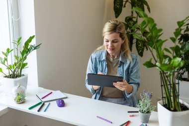 Ofisinde dijital tablet kullanan genç bir iş kadını.