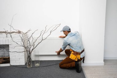 Adamın biri evin ısıtmasını, radyatörünü değiştiriyor. Modern ısıtma kavramı, eskisinin yerine yenisini koymak. Evde sıcaklık var..