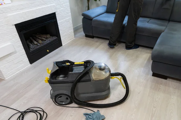 Hand cleaning a sofa with a steam cleaner, Home cleaning concept.