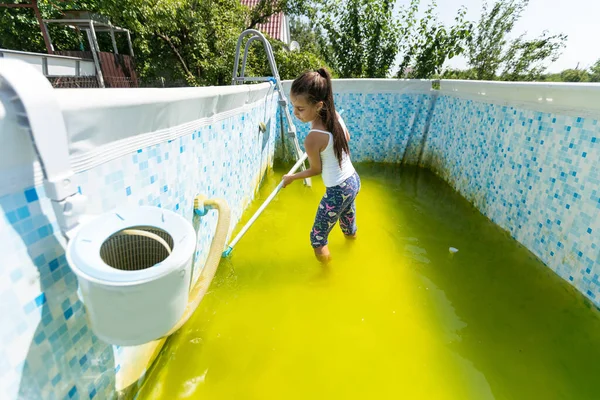 a little girl cleans a very dirty pool.