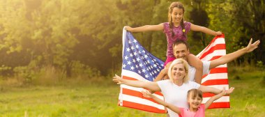Gün batımında Amerika bayrağıyla mutlu bir aile..