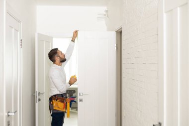 High Angle View Of Male Carpenter With Screwdriver Fixing Door Lock.