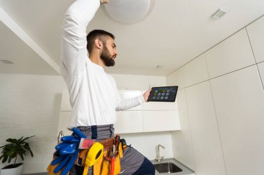 Electrician with tablet indoors, lamp.