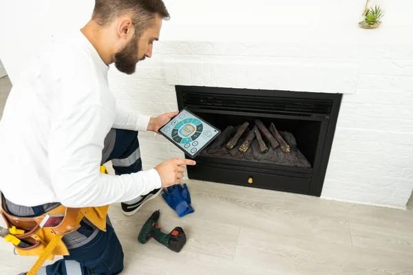 Service technician with tablet repairing a fireplace in a home.
