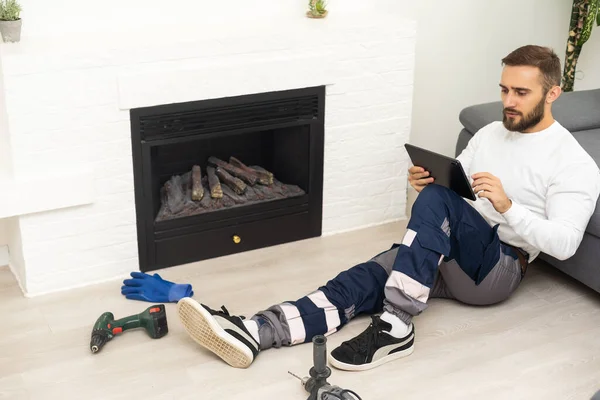 Service technician with tablet repairing a fireplace in a home.