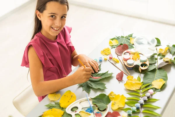 female hands paint autumn leaves on canvas with paints outdoor. High quality photo