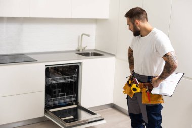 Man repairing a dishwasher with tools.