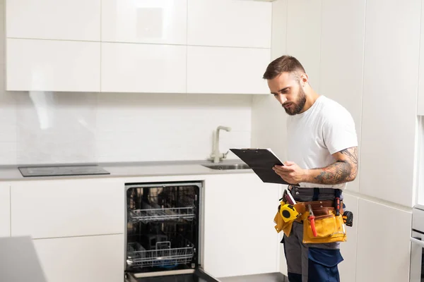 Technician or plumber repairing the dishwasher in a household.
