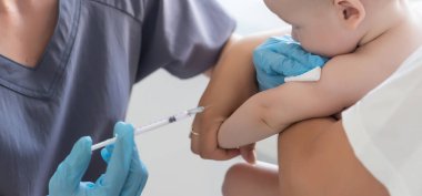 Doktor beyaz arka planda bebek aşısı yapıyor.