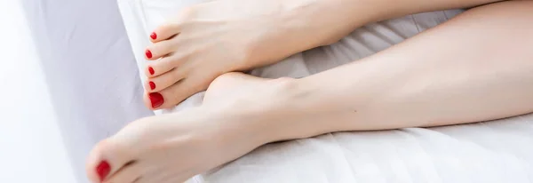 Woman legs on the bed with white bed clothes.