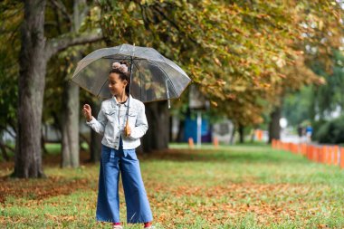 Kid playing out in the rain. Children with umbrella play outdoors in rain. autumn weather