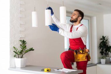 Elektrik işçisi yeni dairede lamba monte ediyor.