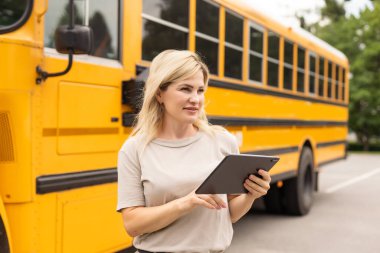 Portrait of positive middle aged woman teacher, psychologist, mentor, therapist, counselor near the school bus.