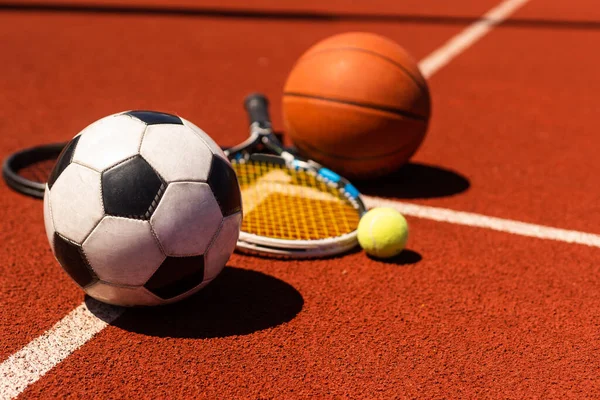 A group of sports equipment on black background including tennis, basketball, and soccer and boxing equipment on a background with copy space.