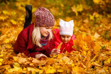 Young mother with her little daughter in an autumn park.
