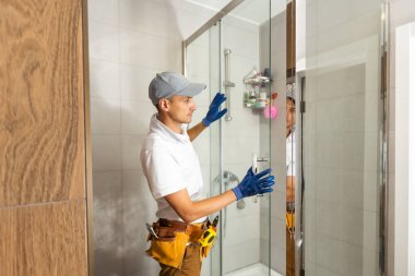 Tesisatçı duş kabini kuruyor, banyoda çalışıyor.