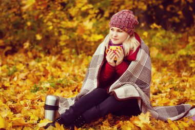 Sonbahar kadın kahve içme. Genç kadının tek kullanımlık kahve Kupası sonbahar ortamındaki sıcak içecek kavramı düşmek.