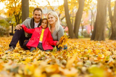 Happy family is sitting in beautiful autumn park