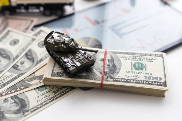 Dolar banknotlarının arka planında oyuncak tankı.