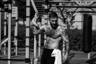 Genç adam parkta egzersiz makinesinin üzerinde antrenman yapıyor..