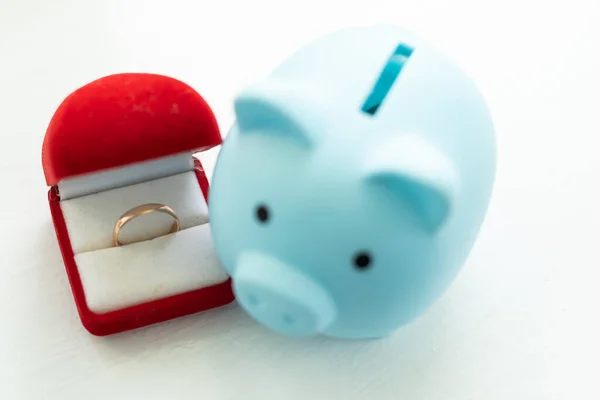 piggy bank with a ten dollar bill inside and a box with wedding ring. Expensive relationship.