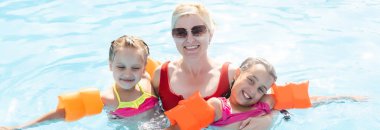 Denizde tropik bir tatil köyünde mavi yüzme havuzunda oynayan mutlu bir aile. Yaz tatilleri konsepti