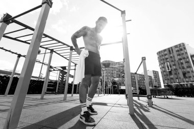 Genç adam parkta egzersiz makinesinin üzerinde antrenman yapıyor..