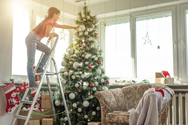 Kleines Mädchen Auf Einer Leiter Schmückt Den Weihnachtsbaum — Stockfoto