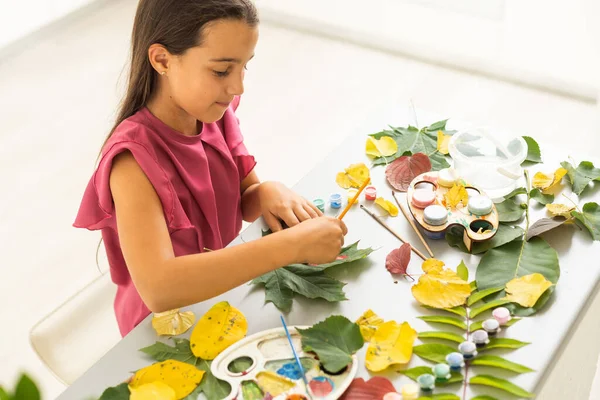 child paints leaves with paints, draws a picture, making prints of leaves. Childrens creativity in nature. Outdoor. Summer. High quality photo