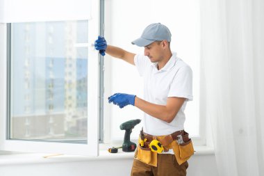 a repairman repairs, adjusts or installs metal-plastic windows in the apartment. glazing of balconies, loggias, verandas in house. production of double-glazed windows to individual sizes