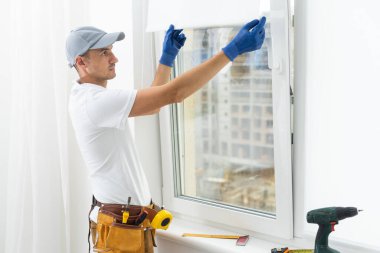 a repairman repairs, adjusts or installs metal-plastic windows in the apartment. glazing of balconies, loggias, verandas in house. production of double-glazed windows to individual sizes