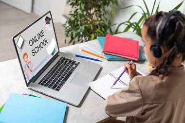 Çevrimiçi Eğitim. Evde dizüstü bilgisayarla ve kablosuz kulaklıkla çalışan sevimli bir kız öğretmeniyle internet dersi alan sevimli bir çocuk karantina süresince mesafeyi öğrenmenin tadını çıkaran, boş bir alan..