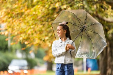 Kid playing out in the rain. Children with umbrella play outdoors in rain. autumn weather