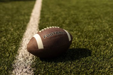 American football ball on the grass of a stadium.