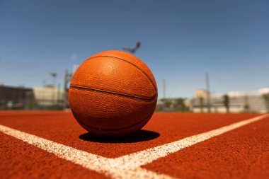 Top view orange ball for basketball lying on the rubber sport court. Sport red ground outdoor in the yard.
