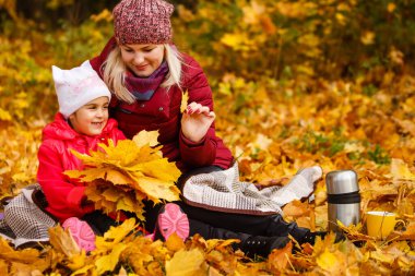 Genç anne ve küçük kızı sonbahar parkında..