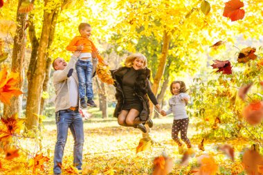 family, childhood, season and people concept - happy family playing with autumn leaves in park. High quality photo