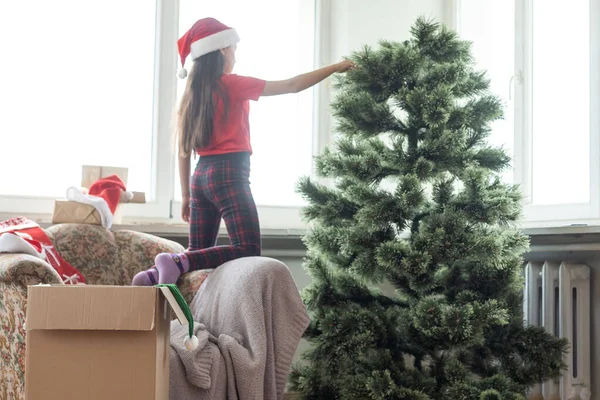 女の子は人工的なクリスマスツリーを作る — ストック写真