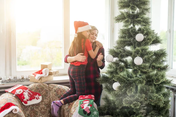 家を飾る母親と子供は大きな木造の家でクリスマスツリーのおもちゃをクリスマスツリーに掛けます — ストック写真