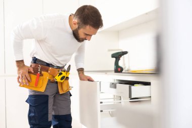 Genç adam mutfak mobilyalarını monte ediyor..
