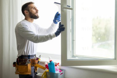 Genç bir adam pencereyi temizler. Pencere temizleme kavramı.