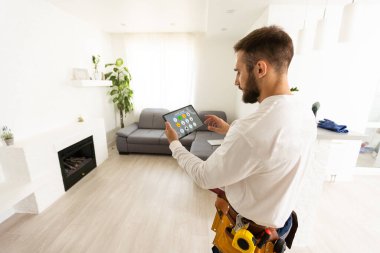 Mutfakta çalışırken elinde tabletle gülümseyen beyaz bir erkek işçi..