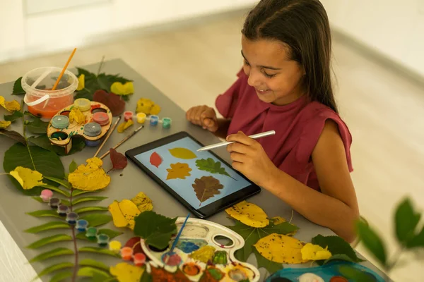 child paints leaves with paints, draws a picture, making prints of leaves. Childrens creativity in nature. Outdoor. Summer. High quality photo