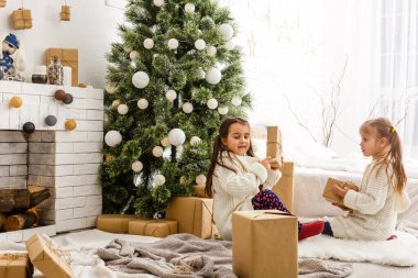 Çocuklar küçük kız hediye kutuları iç arka plan tutun. Ne büyük bir sürpriz. Küçük şirin kızlar tatil hediye aldı. En iyi oyuncaklar ve Noel hediyeleri. Çocuk arkadaş onların hediyeler açma heyecanlı.
